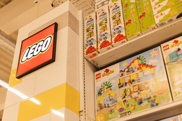 Fototapeta premium Chemnitz, Germany - March 14, 2026: Shelves feature various Lego toy sets for sale in a retail store. The Lego logo is visible, indicating the brand. Shoppers browse the colorful selections