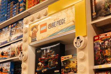 Fototapeta premium Chemnitz, Germany - March 14, 2026: Shelves show Lego sets featuring One Piece branding. Customers browse through various options for creative play. Scene set in a busy retail store filled with toys