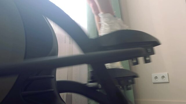 Woman training on elliptical machine at home in soft light
