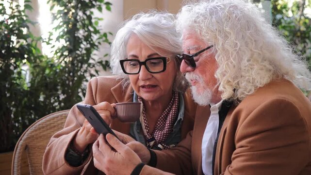An elderly couple engages in a delightful interaction as they explore captivating content on a smartphone together, creating a memorable bonding experience filled with laughter and joy.