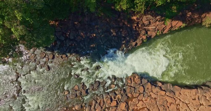 Aerial view of Tad Pha Suam Waterfall near Pakse in Champasak Southern Laos. Water flows over unique column like rock formations surrounded by lush tropical forest, creating a scenic natural