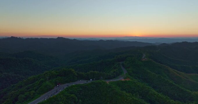 Aerial view of a scenic winding mountain road cutting through lush green hills in Nan, Thailand. The dramatic curves form the shape of the number three, making it a popular tourist attraction.