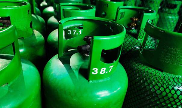Close-up of green LPG gas cylinders with valves in storage. Concept of fuel supply, energy distribution, safety handling, and industrial or household gas usage.