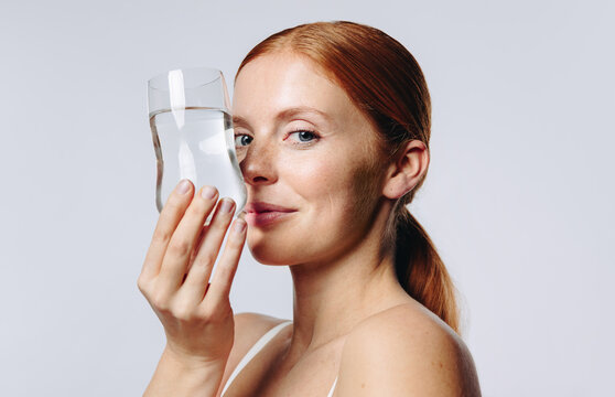 Woman lifts glass of water to her face