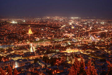 Breathtaking Night Panorama of Tbilisi: A Sea of Golden City Lights and Historic Landmarks. High-Angle Cityscape of Tbilisi at Twilight with Illuminated Holy Trinity Cathedral. The Glowing Heart of  © Iliya Mitsk