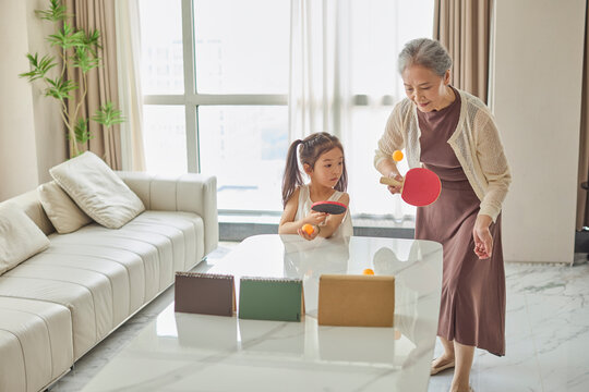 Grandma teaching her granddaughter how to play ping pong