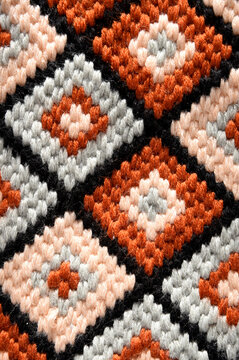 Close up of bargello needlepoint embroidery with geometric diamond pattern, traditional florentine flame stitch on canvas, colorful wool textile texture for interior design background