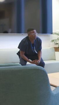 Vertical video: Reacting to phone, staff rising in scrubs, pointing at peer in lounge