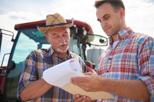Two farmers discussing data from clipboard on the farm