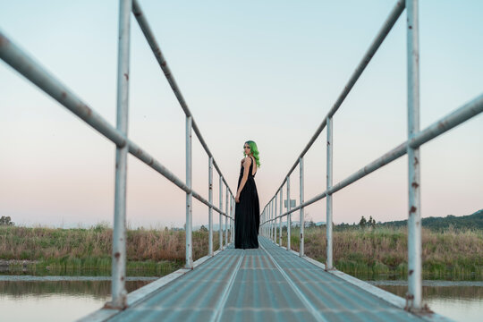 Young woman with dyed green hair standing on a footbridge looking back