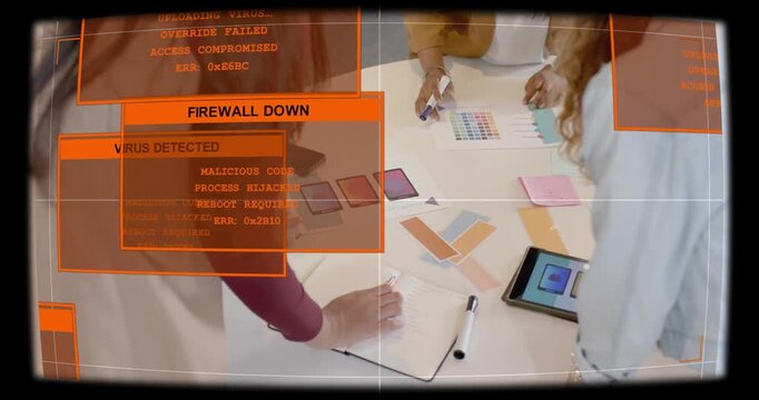 Design team arranging swatches and tapping tablet in meeting, tablet raising orange malware alerts