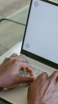 Vertical video: Starting poised, male hands typing on porch, silver laptop crosshairs for work