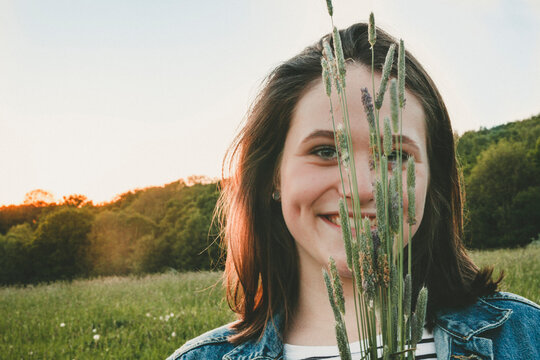 Portrait of smiling teenage girl with grasses at sunset