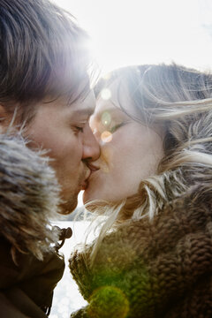 Kissing young couple in winter at backlight