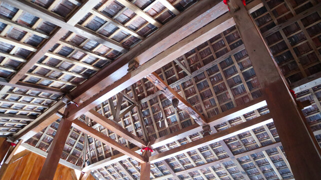 Intricate wooden roof structure with visible beams and rafters from a low angle inside a traditional building