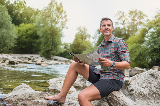 Hiker sitting at riverbank with map