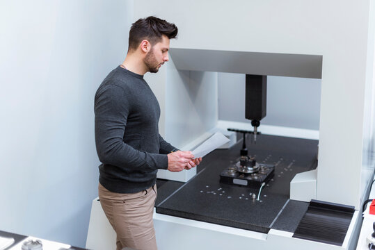Man with paper examining machine in modern factory