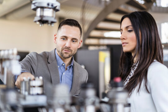 Businessman and businesswoman examining workpieces in factory