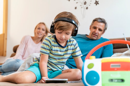 Family on couch at home with boy listening to music with headphones