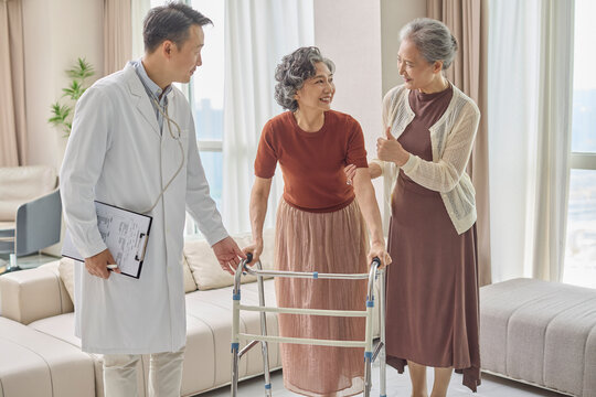 Senior woman using a walking frame under her doctor's supervision