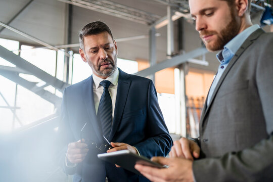 Two businessmen with tablet having a meeting in a factory