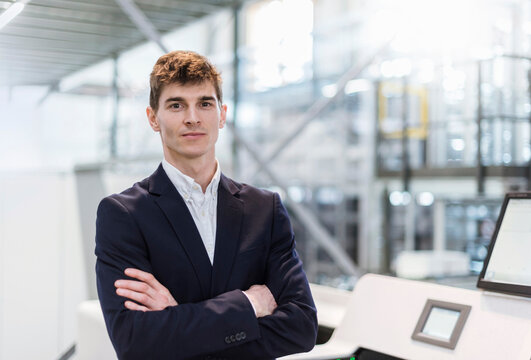 Confident businessman with arms crossed standing in factory