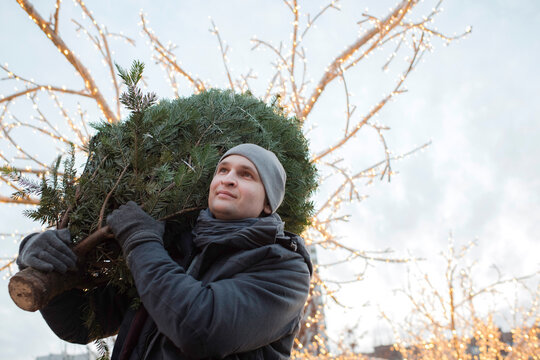 Young man with fir tree on his shoulder