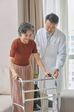 Senior woman using a walking frame under her doctor's supervision