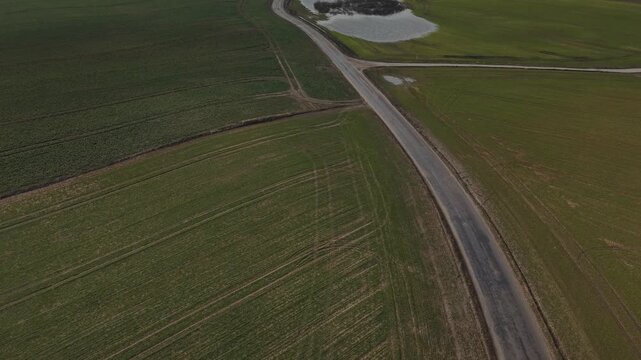 Forward Flight With Tilt‑Up Reveal Over Farmland Road With S-Shaped Curves