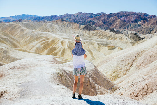 USA, California, Death Valley National Park, Twenty Mule Team Canyon, back view mother carrying baby girl