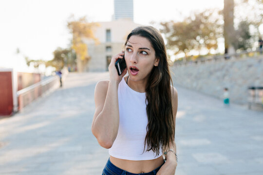Portrait of astonished young woman on the phone