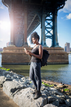 USA, New York City, Brooklyn, woman listening to music under Manhattan Bridge
