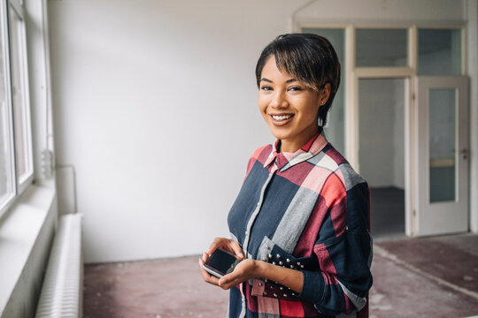 Portrait of smiling young woman holding phablet
