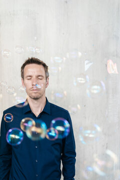 Businessman standing outdoors surrounded by soap bubbles