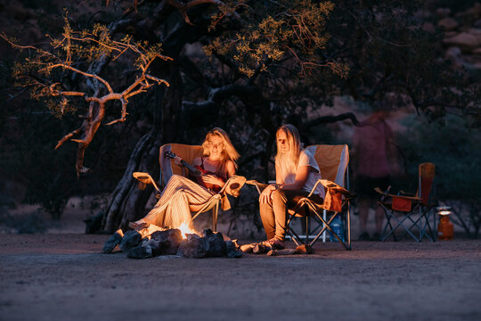 Namibia, friends sitting at campfire playing guitar