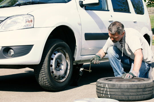 Mature man changing car tires, top view