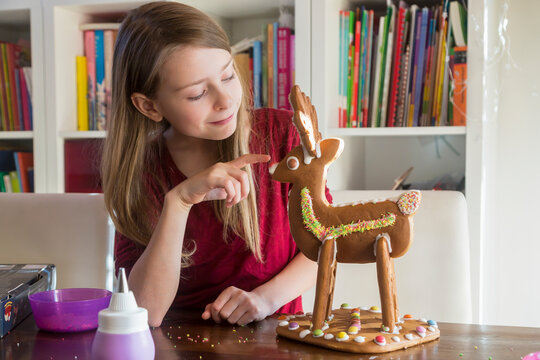 Smiling girl with homemade gingerbread reindeer at home