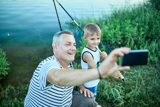 Grandfather and grandson taking selfie with smartphone at lakeshore