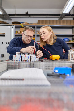 Two electricians working on circuitry in workshop