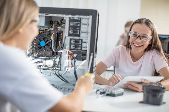 Happy teenage girls assembling computer in class