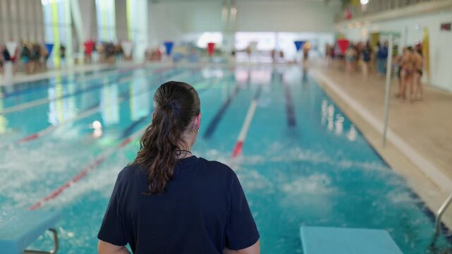 Female coach observing swimmers diving at competition