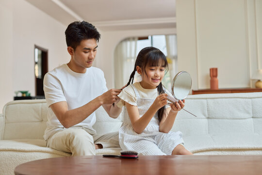 A father braids his daughter's hair
