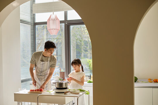 A stay-at-home dad and his daughter cooking in the kitchen