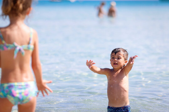 Bimbo gioca a palla sulla spiaggia di Cala Brandinchi, San Teodoro, Olbia, Sardegna, Italia, Europa