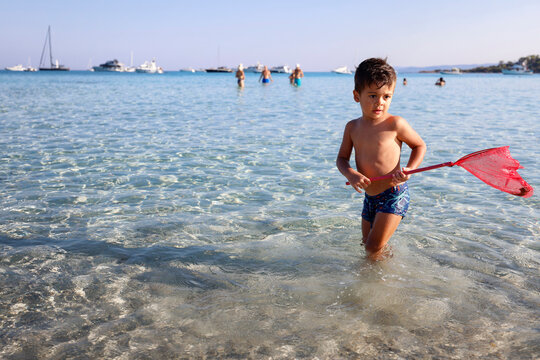 Bimbo gioca con retino sulla spiaggia di Cala Brandinchi, San Teodoro, Olbia, Sardegna, Italia, Europa