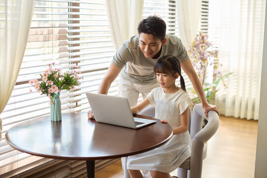 A girl taking an online lesson, with her dad accompanying her