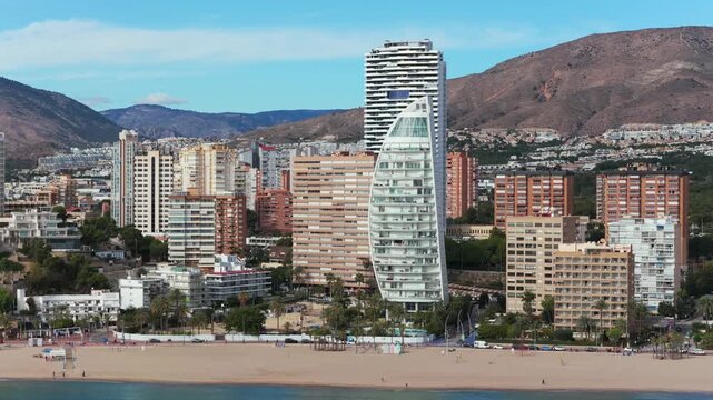 Modern beachfront skyscrapers like the Delfin Tower on Poniente beach in Benidorm, Spain. Aerial backward, copy space