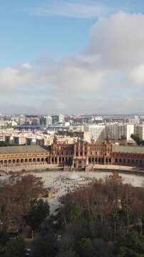 Vertical aerial showing Plaza de Espa&ntilde;a towering above the lush gardens of Maria Luisa Park.