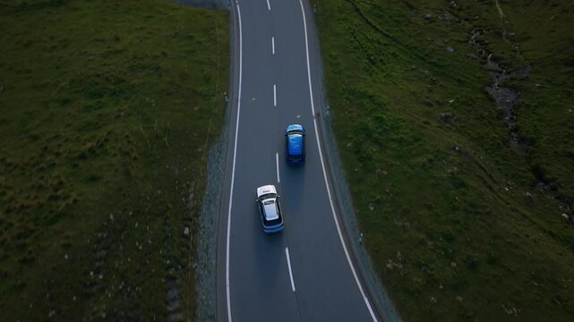 Two cars driving on the winding Julier Pass road in the Swiss Alps, Switzerland. Aerial top-down view