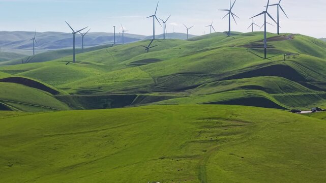Aerial view of wind turbines spinning on rolling green hills at the Altamont Pass Wind Farm in California, generating clean, sustainable, and renewable energy for the future power grid